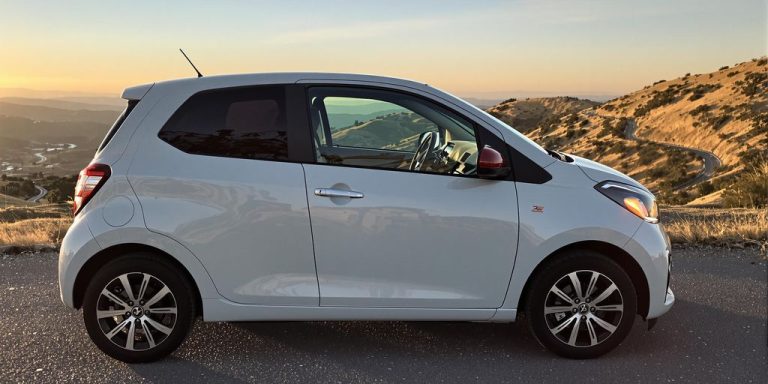 Compact car parked on scenic, affordable road trip.