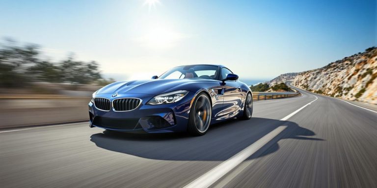Sleek blue BMW speeding on scenic coastal road.