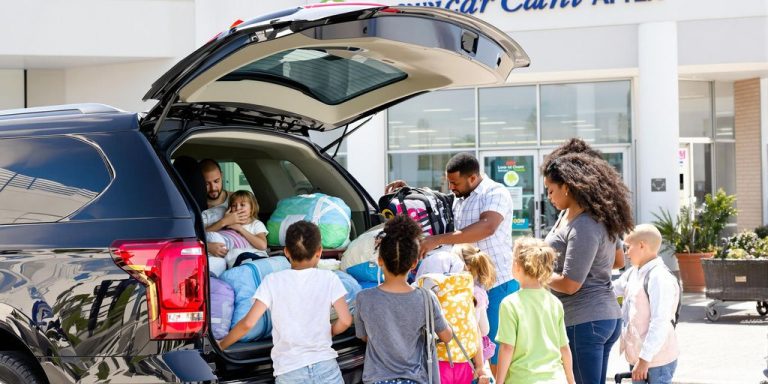 Family loads luggage into large rental SUV.